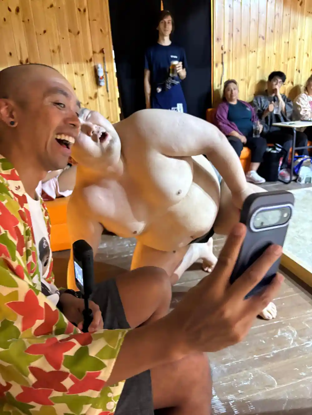 Shirtless man eating or drinking indoors at event