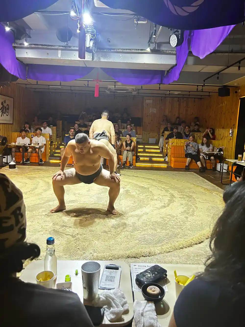 Sumo wrestler in crouching position on sand arena