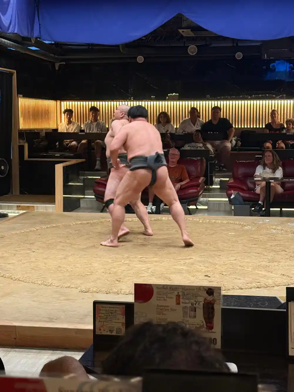 Sumo wrestler in fighting stance during indoor match
