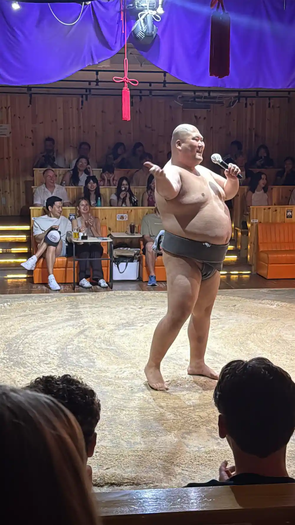 Sumo wrestler holding microphone during indoor competition