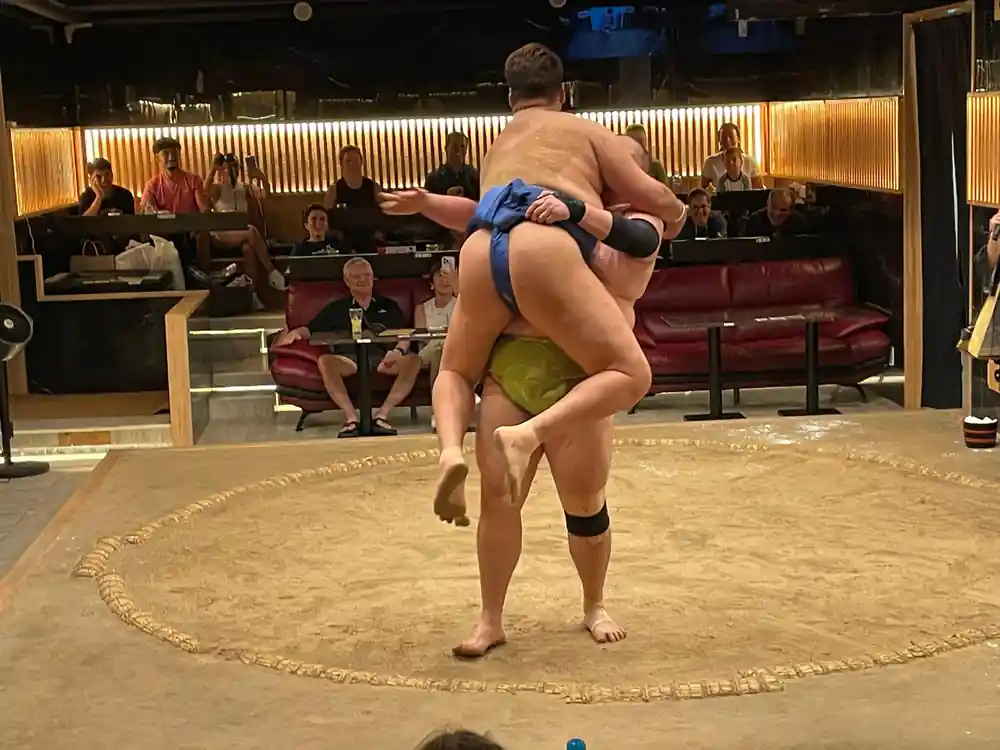 Sumo wrestler lifting opponent during match performance