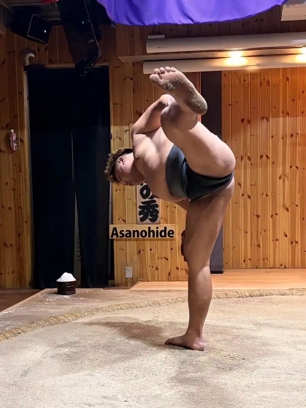 Sumo wrestler performing handstand demonstration indoors
