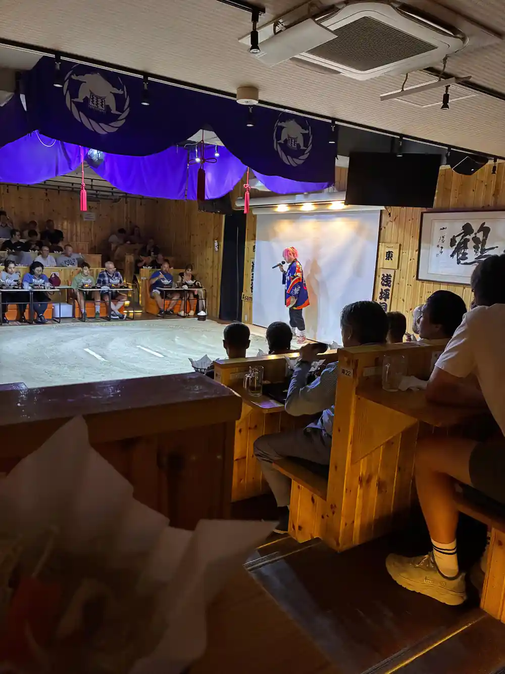 Sumo wrestler performing on sand arena for seated audience