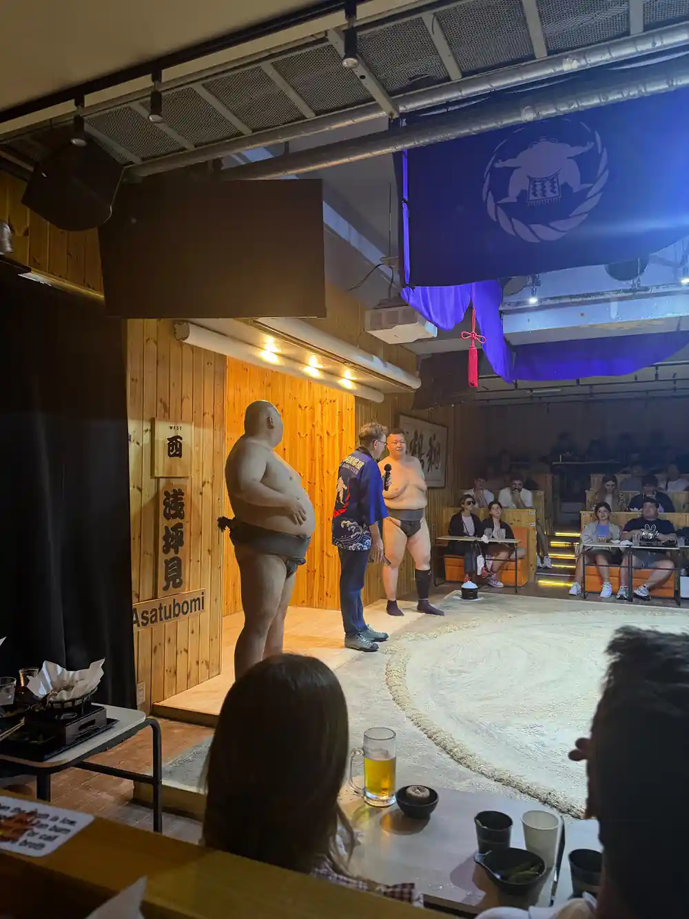 Sumo wrestlers and officials at wooden doorway entrance