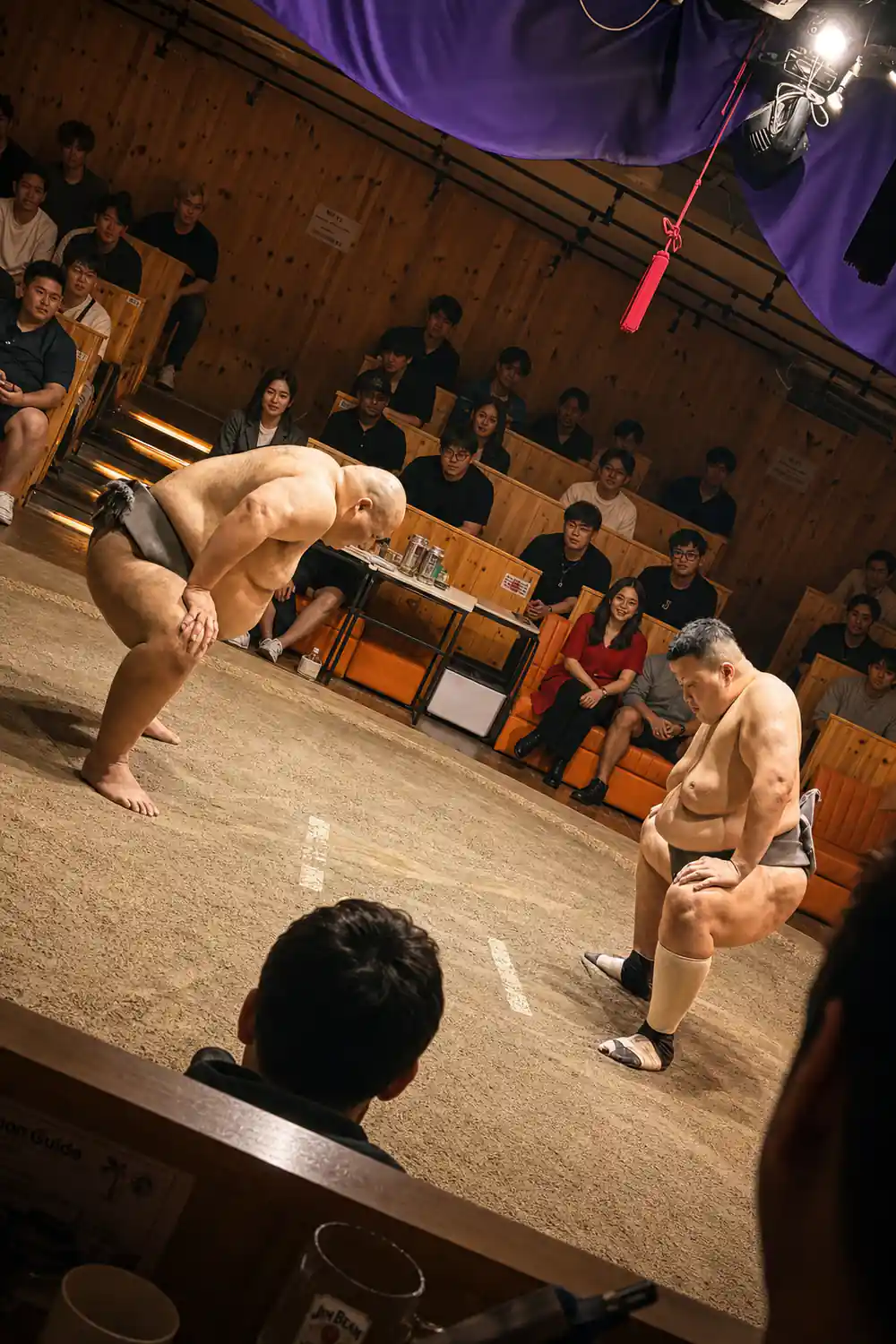 Sumo wrestlers performing in indoor arena with spectators