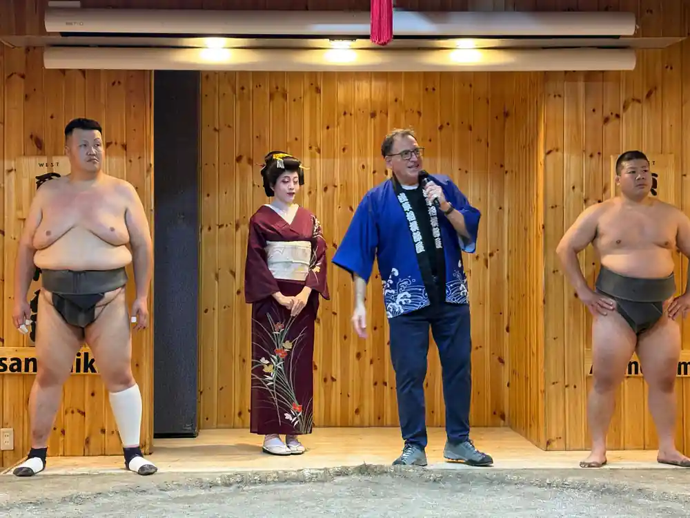 Sumo wrestlers posing with woman in traditional kimono