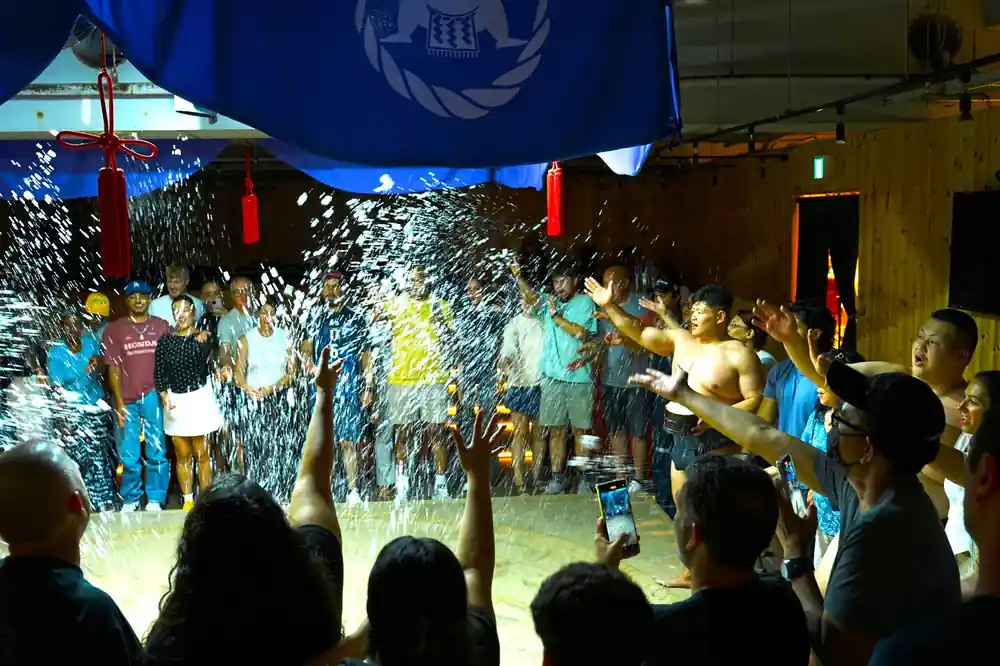 Sumo wrestlers in ring with crowd watching and water effects