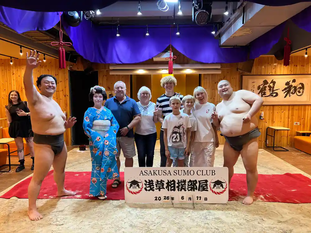Sumo wrestlers and visitors posing with club banner