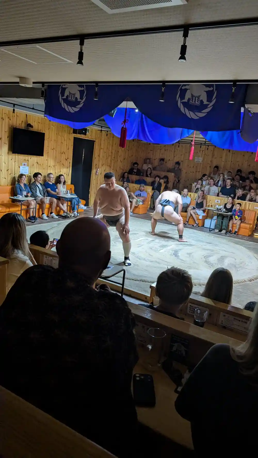Two sumo wrestlers in competition ring viewed from audience