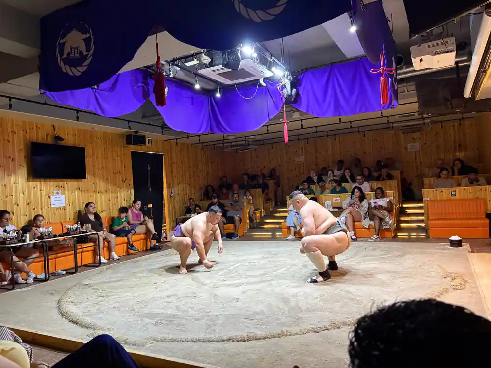 Two sumo wrestlers grappling during indoor match