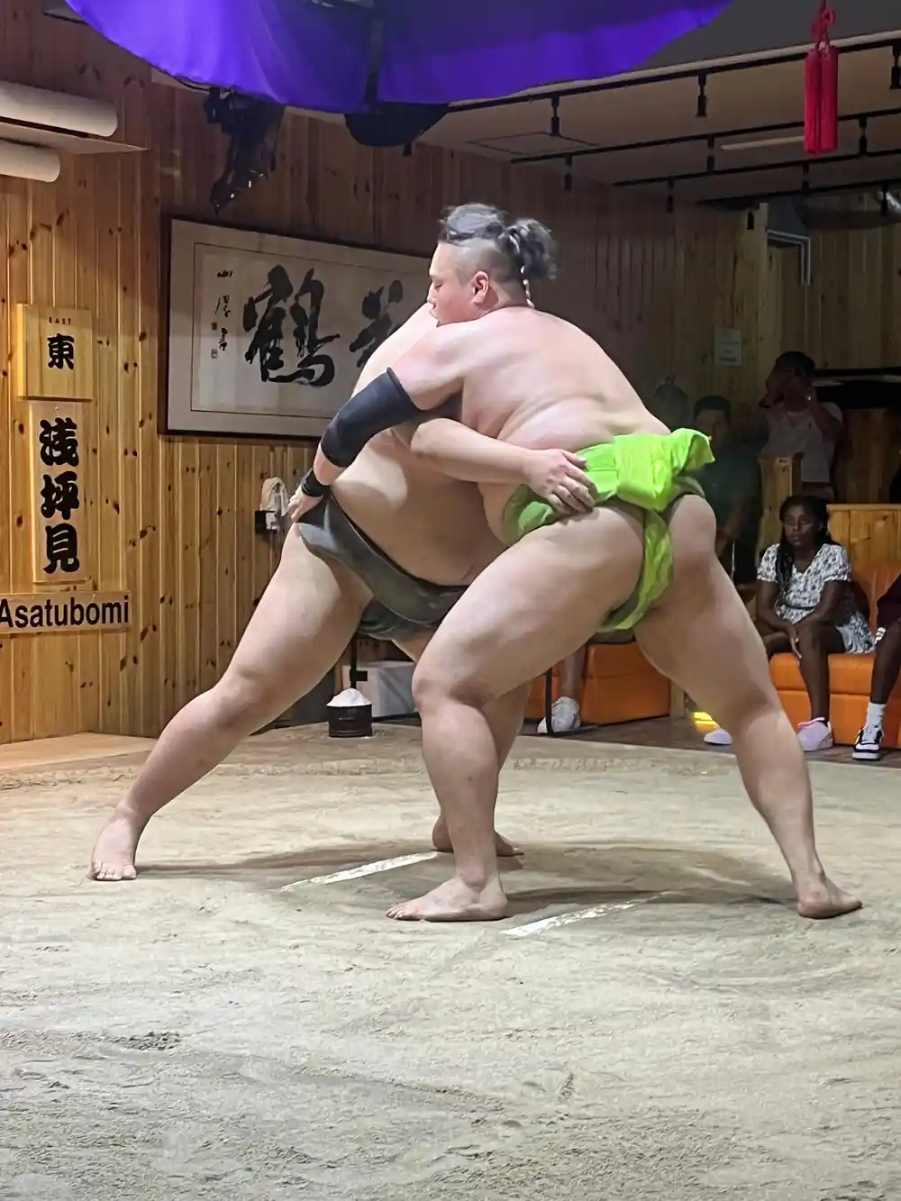 Two sumo wrestlers grappling during match in ring