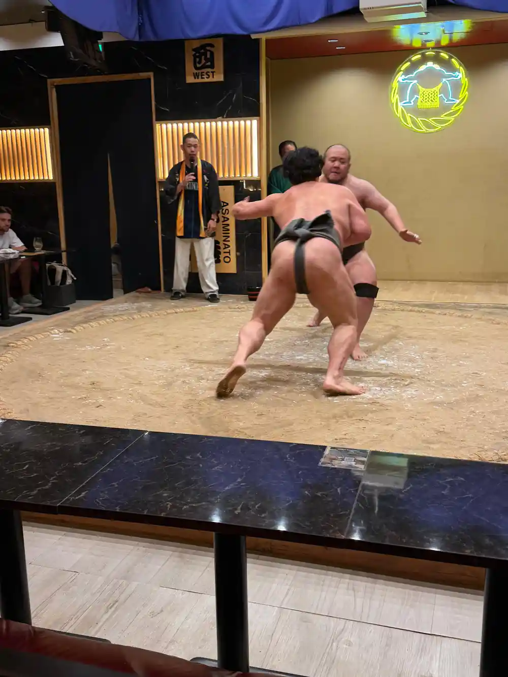 Two sumo wrestlers grappling on training mat indoors