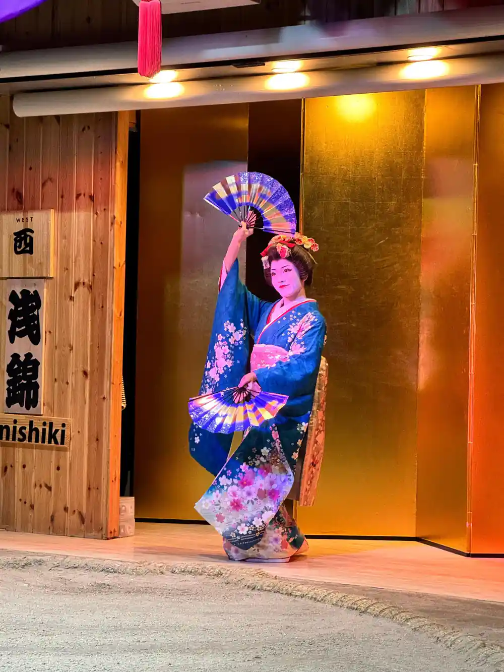 Woman in colorful kimono with fan at wooden doorway