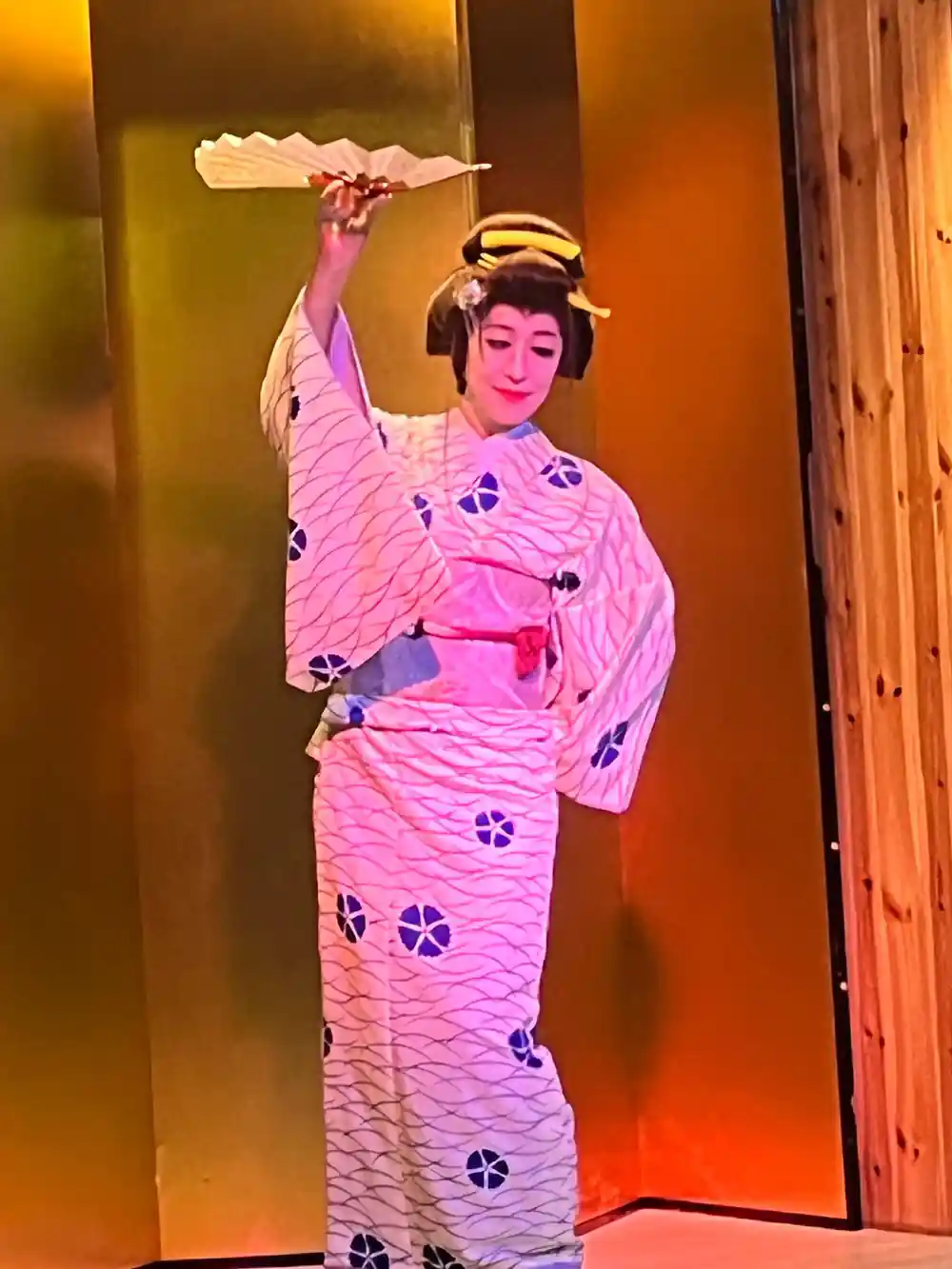 Woman in pink patterned kimono performing with fan