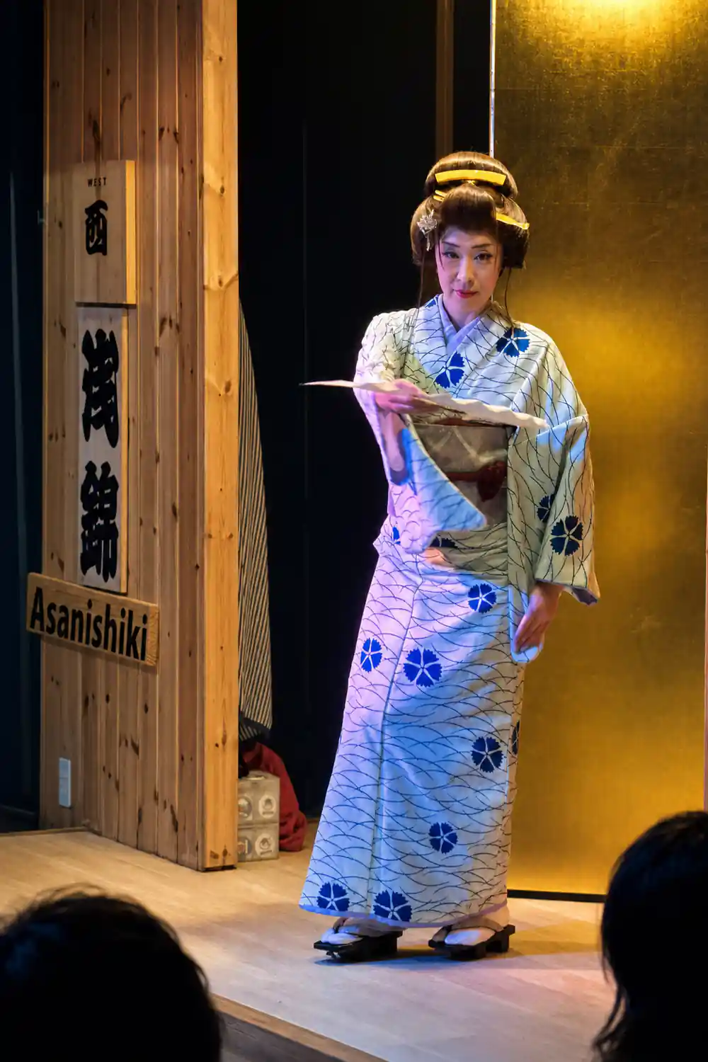 Woman in traditional Japanese kimono holding fan on stage